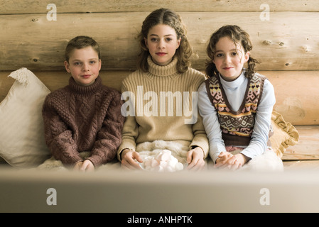 Drei junge Geschwister vor dem Fernseher und Essen marshmallows Stockfoto