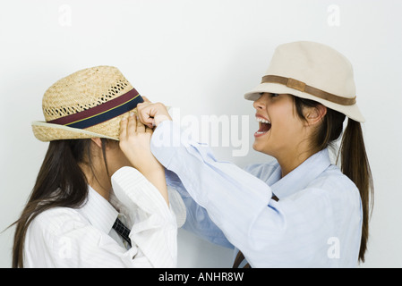 Teenager-Mädchen ziehen Hut über ihre Freundin Gesicht, lachen Stockfoto