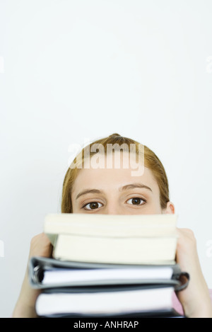 Junge Frau, Blick in die Kamera über Stapel von Büchern Stockfoto