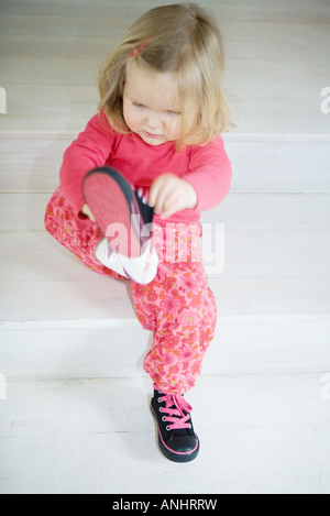 Blonde Kleinkind Mädchen anziehen der Schuhe, in voller Länge Stockfoto