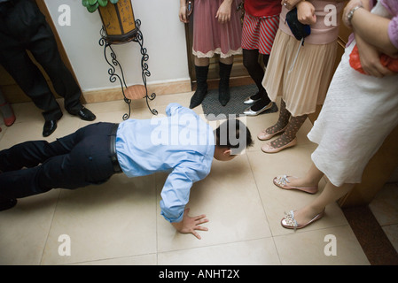 Chinesische Hochzeit Bräutigam doing Push-ups während Frauen Uhr Stockfoto