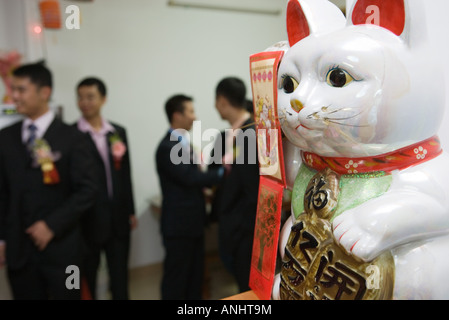 Nahaufnahme von Maneki Neko Figur, Menschen, die im Hintergrund stehen Stockfoto