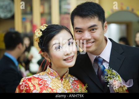 Brautpaar in die Kamera Lächeln, Braut in traditionelle chinesische Kleidung gekleidet Stockfoto