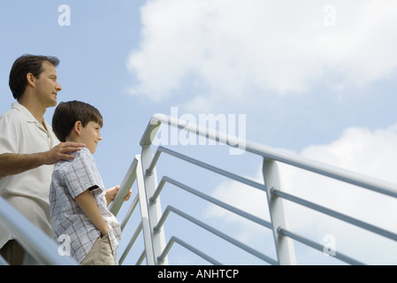 Vater und Sohn durch Geländer stehen niedrige Blick auf Himmel, Winkel Ansicht Stockfoto