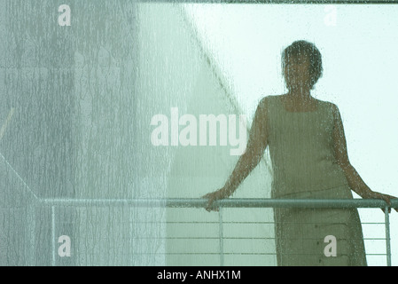 Silhouette der Frau, die durch Fenster in Regen