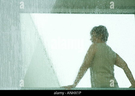 Silhouette der Frau, durch nasse Fenster sehen, Rückansicht
