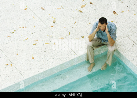 Mann, sitzend mit Füße im Pool, Kopf, hohen Winkel Ansicht Stockfoto