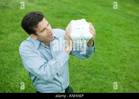 Mann-Betrieb-Sparschwein überrascht kopfüber, auf der Suche Stockfoto