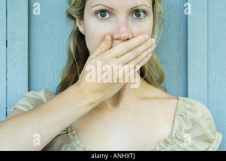 Frau den Mund mit der Hand, Blick in die Kamera mit großen Augen Stockfoto