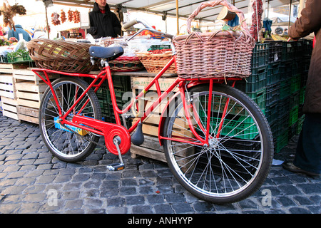 Fahrrad und Stroh Korb rot Push geparkt auf Platz gegen Obst stall Stockfoto