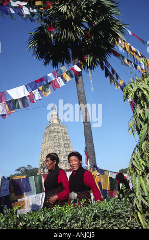 Tibetisch-buddhistische Pilger im traditionellen Kleid, die den Mahabodhi-Tempel umlaufen, der mit Gebetflaggen übersät ist, um Verdienst zu erlangen, Bodh Gaya, Bihar, Indien Stockfoto