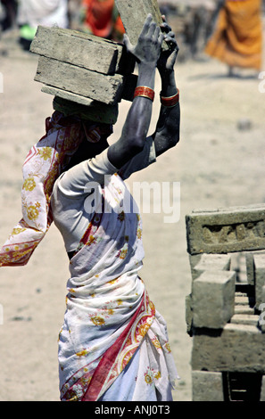 Ein weiblicher Arbeiter ladet mit neu gefeuerten Backsteinen auf dem Kopf in einer Ziegelfabrik in Pune, Maharashtra, Indien Stockfoto