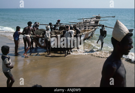 Nolia-Fischer, die ihre traditionellen weißen Hüte tragen, starten ein kleines Fischerboot in den Indischen Ozean vor der Küste von Odisha, Puri, Indien Stockfoto