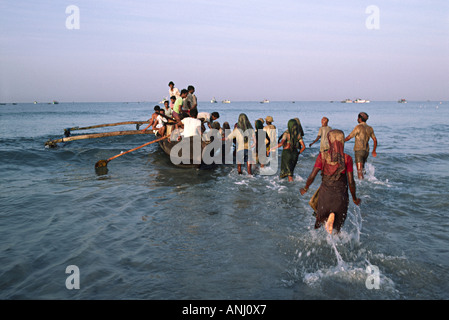 Dorfhändler und -Träger wehten zu einem traditionellen Fischerboot, das den Tagesfang an der Küste Keralas zum Markt brachte. Südindien Stockfoto