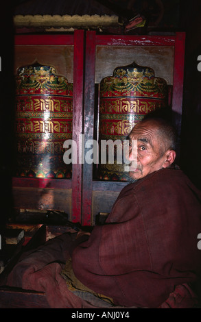 Porträt eines alten tibetischen Monchs, der traditionelle buddhistische Gebeträder in einem Kloster in der abgelegenen Region Ladakh in Nordindien dreht Stockfoto