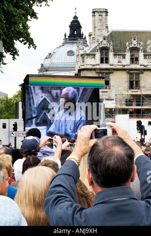 Die Menschenmenge Uhr Nelson Mandela auf einem großen Bildschirm bei der Enthüllung der Statue in Parliament Square, London, 2007. Stockfoto