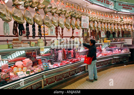 Kunde kauft in einem Stall mit Essen, Käse, Wurst und spanischen Schinken (Jamón Serrano) am Mercado Central oder Central Market Stockfoto