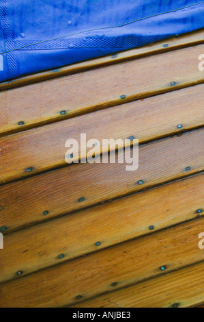 Nahaufnahme von Holzboot, bedeckt mit einer nassen, blaue Plane in Tenby Hafen, Pembrokeshire, Wales, UK Stockfoto