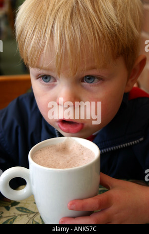 3 Jahre alter Junge Tasse heiße Schokolade in einem Café zu trinken Stockfoto