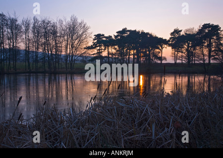 Sonnenuntergang über dem Eis bedeckt See in Parham Park in der Nähe von Storrington, West Sussex, England UK 2007 Stockfoto