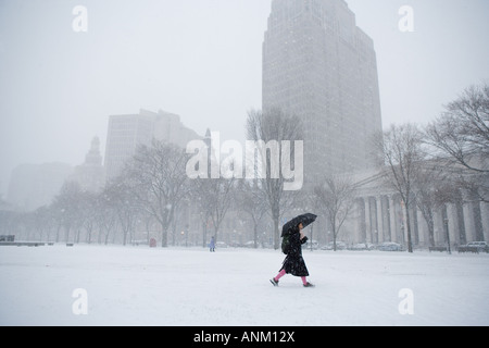 Eine Frau mit einem Regenschirm macht ihren Weg über das Grün in New Haven, Connecticut, USA, während eines Schneesturms. Stockfoto