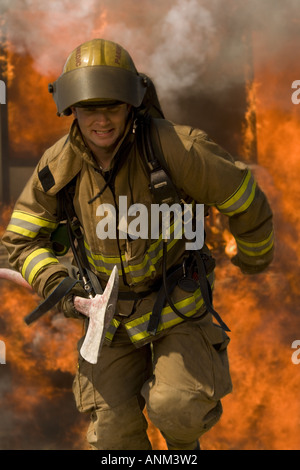 Feuerwehrmann durch Feuer mit einer Axt Stockfoto