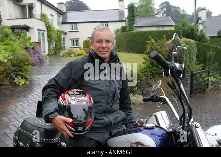 65 Jahre alter Mann mit Harley Davidson Motorrad außerhalb seines Hauses Leute Lifestyle Wales Stockfoto