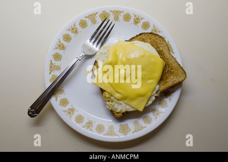 Spiegelei mit amerikanischer Käse auf Toast auf einem weißen Teller mit einer Gabel Stockfoto