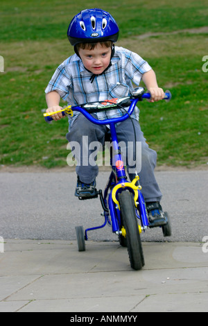 sechs-jährigen, mit seinem Fahrrad mit Stabalisers ausgestattet. Arnot Hill Park, Arnold, Nottinghamshire Stockfoto