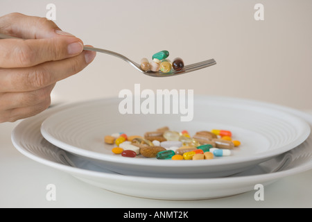 Mann isst Pillen auf Gabel Stockfoto