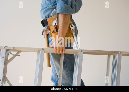 Mann trägt Werkzeuggürtel und Betriebs-Leiter Stockfoto