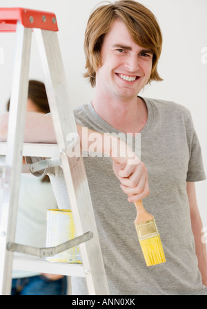 Mann hält Pinsel neben Leiter Stockfoto