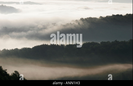 Graue Landschaft von bewaldeten Hügeln und Tälern mit Nebel und Wolken in der französischen Landschaft Stockfoto