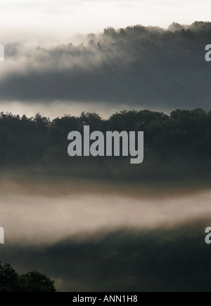 Graue Landschaft von bewaldeten Hügeln und Tälern mit Nebel und Wolken in der französischen Landschaft Stockfoto