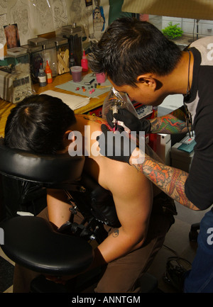 Tattoo-Künstler arbeitet an einer großen Drachen Tattoo auf Rücken eines Mannes. Stockfoto