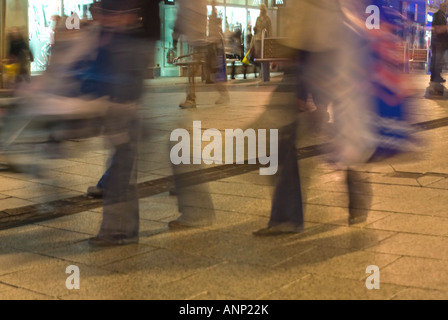 Horizontale Nahaufnahme der Völker Füße und Einkaufstaschen während der Rush Hour in einer Innenstadt in der Nacht. Stockfoto