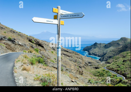 La Gomera, Kanarische Inseln. Am Straßenrand Wegweiser oberhalb Playa De La Caleta. Schneebedeckte Pico del Teide auf Teneriffa in Ferne Stockfoto