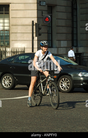 Summer Street Scene Frau Radfahrerin trägt Schutzhelm Reitrad mitten im geschäftigen Verkehr an der Bank Road Junction City of London England UK Stockfoto