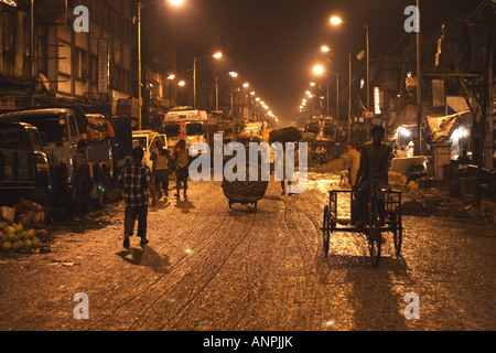 Ein Mann reitet ein Dreirad auf einer Straße nahe der Großmarkt für Obst und Gemüse in Kolkata, Indien. Stockfoto