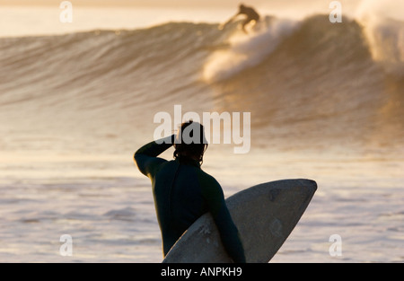 männliche Surfer steht am Ufer mit Surfbrett und Uhren Wellen bei Rincon Point, California Stockfoto