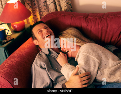 Junges Paar glücklich kuscheln und Lachen gemeinsam auf ihrem Wohnzimmer Sofa zu Hause Stockfoto