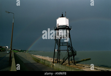 Regenbogen im dunklen Himmel nach Sturm mit Leuchtturm am Ufer des Meeres (doppelter Regenbogen, einer fast verklungen) Stockfoto