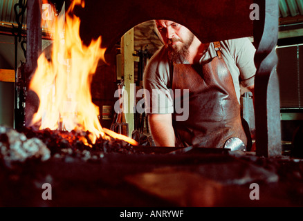 Junge Schmiede arbeiten mit Feuer und hammer in der Schmiede. Stockfoto