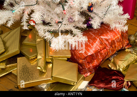 Viele gold verpackte Weihnachtsgeschenke Erdgeschoss aufgetürmt unter einem weißen Kunststoff künstlichen Weihnachtsbaum, Heiligabend, am Morgen Stockfoto