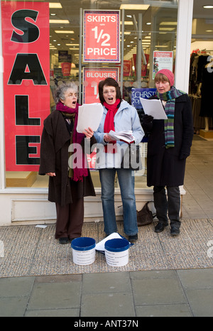 drei Frauen singen Weihnachtslieder auf der Strasse vor Modegeschäft Verkauf Werbung Stockfoto