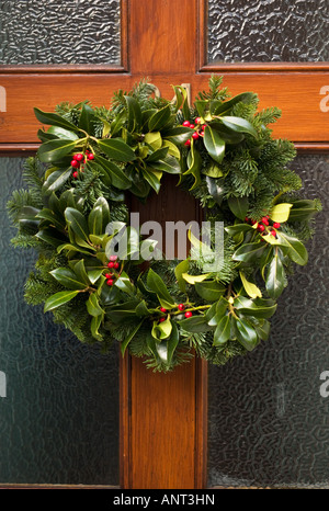 Christmas Holly und Tanne Blätter Kranz auf eine Holztür, ein Echo der heidnische vorchristliche Sonnenwende Rituale und Bräuche - UK Stockfoto