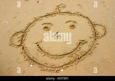 lächelndes Gesicht gezeichnet im Sand am Strand Stockfoto