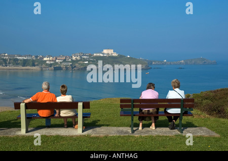 zwei Paare sitzen auf Bänken mit Blick auf das Meer in Newqauy, england Stockfoto