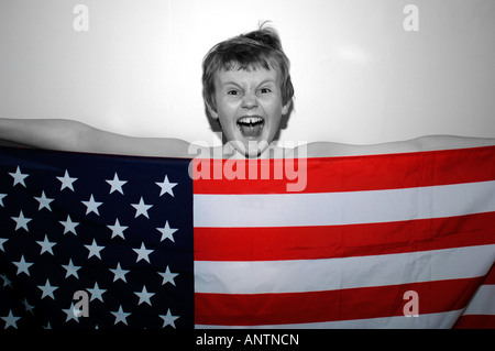 Ein 13 Jahre alter Junge hinter der amerikanischen Stars & Streifen-Flagge, die er in der Hand. Stockfoto