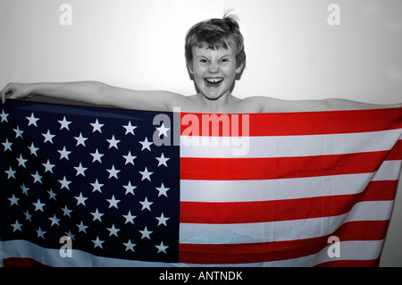 Ein 13 Jahre alter Junge hinter der amerikanischen Stars & Streifen-Flagge, die er in der Hand. Stockfoto